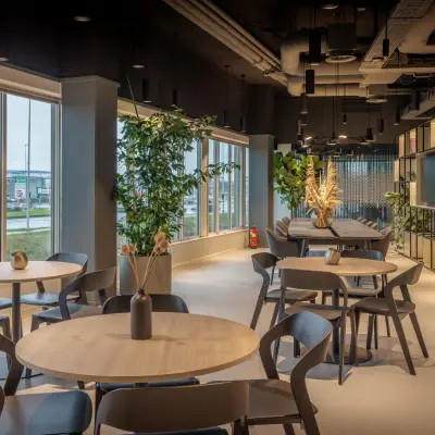 Moderne en licht ingerichte kantoorruimte aan de Herikerbergweg 290 in Amsterdam Zuid-Oost, met ronde tafels en een groene inrichting. Geschikt voor huur en flexibele werkplekken.