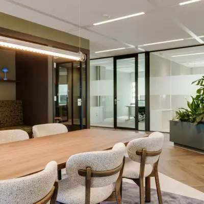 Moderne kantoorruimte op Herikerbergweg 290, Amsterdam Zuid-Oost, met houten tafel en comfortabele stoelen, ruime indeling, glazen wanden en groene planten. Ideaal voor kantoorruimte huren.