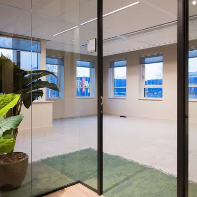 Ongemeubileerd kantoor in Amsterdam Zuid-Oost met moderne glazen deur. Ideaal om kantoorruimte te huren met uitzicht op gebouwen, veel licht en planten voor een frisse uitstraling.