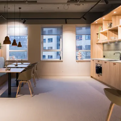 Moderne kantoorruimte huren in Amsterdam Zuid-Oost met strakke keuken, houten accenten en zitgelegenheid. Ideaal voor werk- en ontmoetingsmomenten in een aangename sfeer.