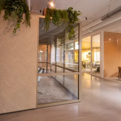 Moderne kantoorruimte op Luttenbergweg 8 in Amsterdam Zuid-Oost met glazen wanden en planten. Ideaal voor bedrijven die een ruim en stijlvol kantoorpand willen huren.