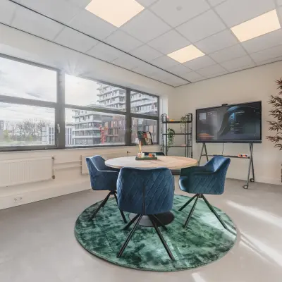 Moderne en lichte kantoorruimte op Paasheuvelweg 20 in Amsterdam Zuid-Oost met grote ramen, een ronde tafel met vier stoelen, een display en planten. Ideaal voor kantoorruimte huren.