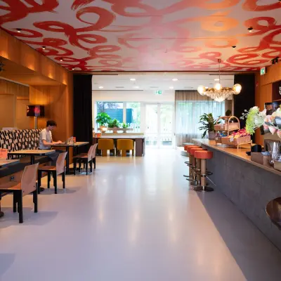 Stijlvolle kantoorruimte huren met kleurrijke accenten op Barbara Strozzilaan 101, Amsterdam Zuidas, waar mensen aan tafels zitten om te werken of te overleggen.