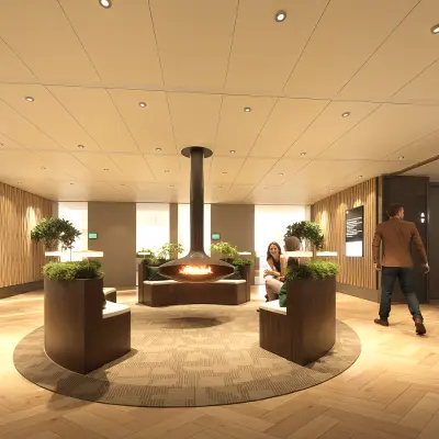 Moderne lobby in het kantoorpand op Claude Debussylaan 80-134, Amsterdam Zuidas, met stijlvolle zitplaatsen en een centraal geplaatste open haard. Het is een uitnodigende ruimte met warme verlichting.