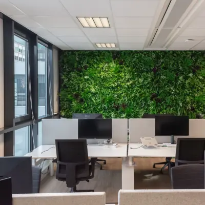 Gemeubileerd kantoor aan De Boelelaan 30 in Amsterdam Zuidas met groene wand, meerdere bureaus en computers, in een lichte werkruimte voor kantoorruimte huren.