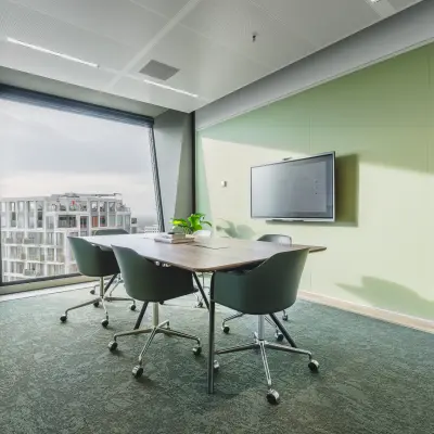 Moderne vergaderruimte in kantoorpand op Hildegard Von Bingenstraat 44, Amsterdam Zuidas, met groene muren, een grote tafel en comfortabele stoelen. Geschikt voor kantoorruimte huren.