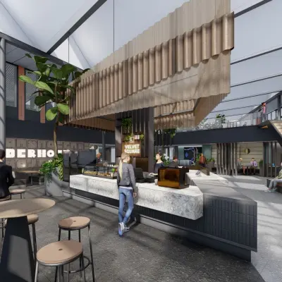 Moderne kantoorruimte in Amsterdam Zuidas met een open vloerplan, voorzien van een centraal koffiepunt en diverse werkplekken. Mensen werken en converseren in een lichte, groene omgeving.