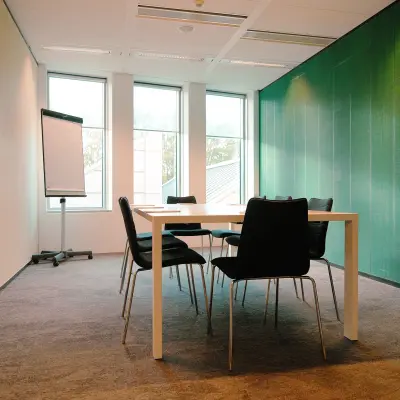 Vergaderruimte in een kantoorpand aan de Jachthavenweg 109, Amsterdam Zuidas, met grote ramen, een tafel en stoelen met zicht op groen. Ideaal voor wie kantoorruimte wil huren.
