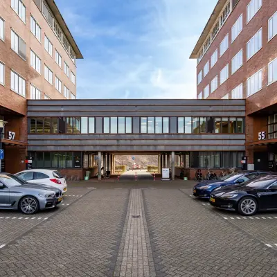 Kantoorpand Het Rietveld 55-59 in Apeldoorn met geparkeerde auto's op het terrein; ideaal voor kantoorruimte huren.