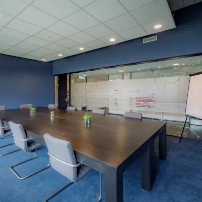Vergaderruimte in Apeldoorn op de Oude Apeldoornseweg 41-45 met moderne meubels en glazen wand. Onderdeel van het kantoorpand, ideaal voor wie kantoorruimte wil huren.