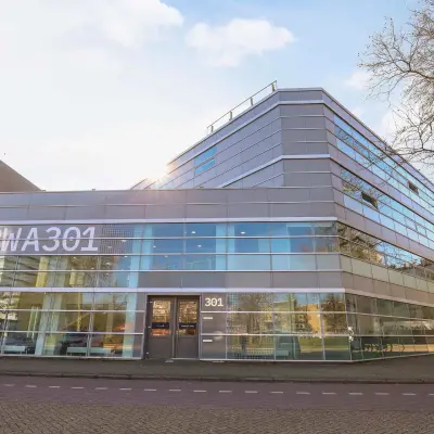 Modern kantoorpand op Prins Willem-Alexanderlaan 301 in Apeldoorn, met glazen gevel en ruime parkeerplaats vooraan. Ideaal als representatieve kantoorruimte voor bedrijven die willen huren.