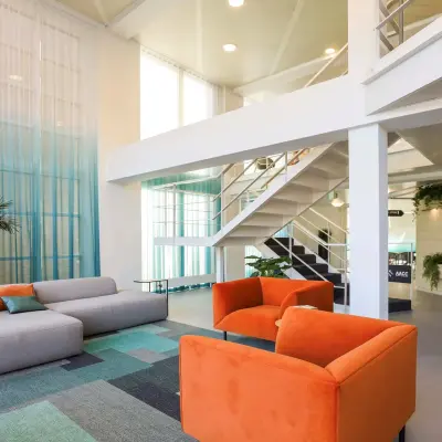 Moderne kantoorruimte op Prins Willem-Alexanderlaan 301, Apeldoorn, met een stijlvolle lounge en kleurrijke meubels. Perfect om te huren als kantoorpand; de lichte omgeving bevordert creativiteit en samenwerking.