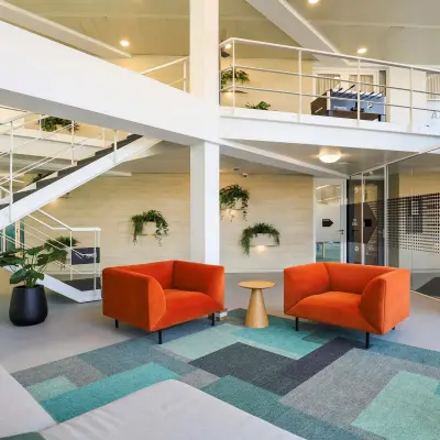 Moderne kantoorruimte te huur aan de Prins Willem-Alexanderlaan 301 in Apeldoorn, met kleurrijke meubels en een open indeling. Het kantoorpand is ingericht met zitgedeeltes en planten voor een frisse werkplek.