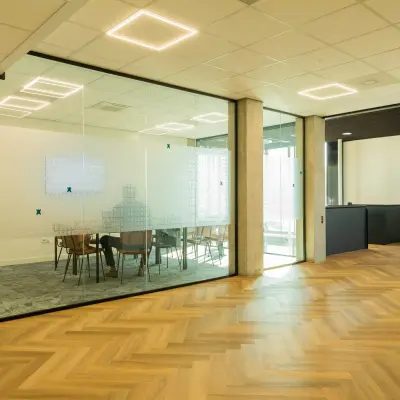 Glazen vergaderruimte in kantoorpand op Prins Willem Alexanderlaan 701, Apeldoorn, met houten vloer en moderne verlichting.