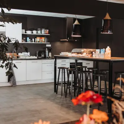 Moderne pantry in een kantoorpand op Vlamoven 34, Arnhem IJsseloord. Ruimte met strak design, voorzien van een hoog tafelblad en krukken, ideaal voor kantoorruimte huren.