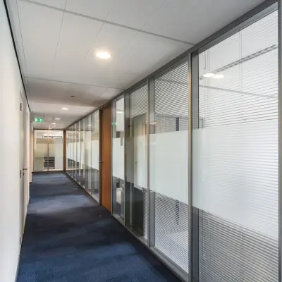 Kantoorpand Arnhem Zuid bij Kronenburgsingel 525 met een moderne gang met glazen wanden en tapijtvloer, geschikt voor kantoorruimte huren.