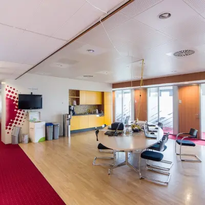 Kantoorruimte huren in Arnhem Zuid met moderne vergadertafel, stoelen, tv-scherm en koffiehoek op Kronenburgsingel 525.