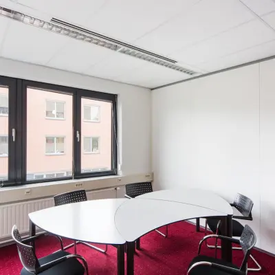 Kantoorruimte huren in Arnhem Zuid aan de Kronenburgsingel 525. Gelegen in een ruim, goed verlicht kantoor met rode vloerbedekking en moderne stoelen rondom een vergadertafel. Ideaal voor zakelijke bijeenkomsten.