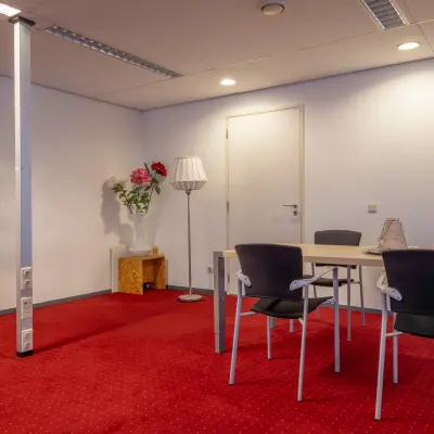 Kantoorruimte huren in Arnhem Zuid aan de Kronenburgsingel 525 met een rode vloerbedekking en enkele stoelen rondom een tafel.