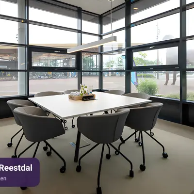Moderne vergaderruimte in Assen met grote ramen en een tafel met stoelen, ideaal voor kantoorruimte huren.