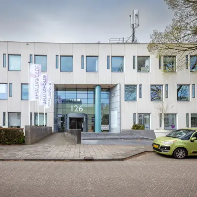 Vooraanzicht van kantoorpand op Amalialaan 126 in Baarn; modern gebouw met strakke gevel en parkeerplaats. Ideaal voor kantoorruimte huren.