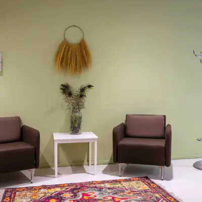 Kantoor op de Amalialaan 126 in Baarn met twee stoelen, een bijzettafel en kleerhanger in kleurrijke ruimte. Optie voor kantoorruimte huren in modern kantoorpand.