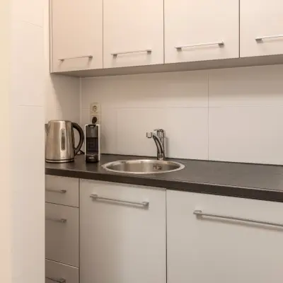 Functionele pantry in een Barendrechts kantoorpand met witte kasten en een donker aanrechtblad, ideaal voor een snelle break tijdens het kantoorwerk.