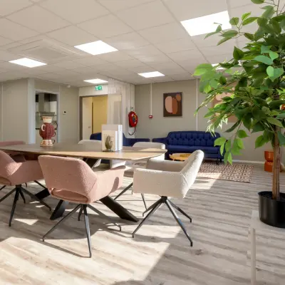 Gezellige werkruimte in een kantoor op Kamerlingh Onnesweg 10, Barendrecht met een tafel, stoelen, bank en planten. Ideale plek voor kantoorruimte huren.