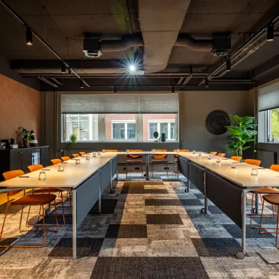Kantoorruimte huren op Baron van Nagellstraat 136 in Barneveld met een moderne uitstraling, inclusief vergadertafels en oranje stoelen, klaar voor gebruik.