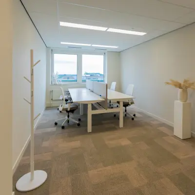 Lichte kantoorruimte aan de Baron van Nagellstraat 136 in Barneveld, met lange tafel en witte stoelen, ideaal voor wie kantoren wil huren.