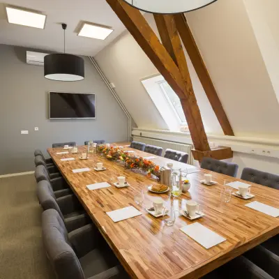 Vergaderruimte in een kantoorpand op Blokstallen 2B, Bergen op Zoom. Ruime tafel met luxe stoelen en groot raam, ideaal voor kantoorruimte huren. Modern ingericht met warme accenten.