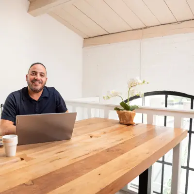Kantoorruimte huren in Bergen op Zoom met een gezellige houten tafel, ideaal voor zakelijk gebruik. Een man werkt op zijn laptop aan de Zuidzijde Haven 39a.