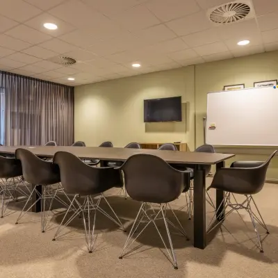 Moderne vergaderruimte in Bodegraven met grote tafel omringd door strakke stoelen en een whiteboard, ideaal voor kantoorruimte huren bij Marktstraat 1-7.