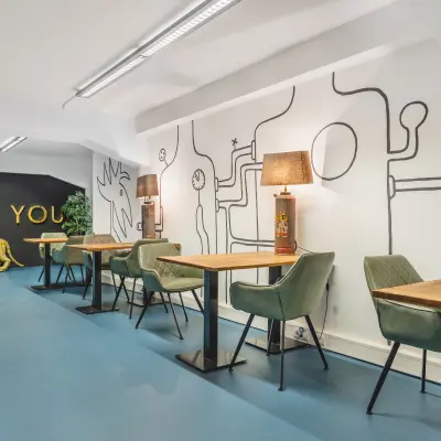 Moderne kantoorruimte te huur op Ceresstraat 13 in Breda Centrum-Station met kleurrijk interieur, beschilderde muren en diverse werkplekken ingericht met groene stoelen en houten tafels.