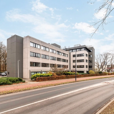 Kantoorpand aan de Heerbaan 14 in Breda Oost-Brabantpark met meerdere verdiepingen, omgeven door bomen, langs een weg. Perfecte locatie voor kantoorruimte huren.