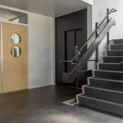Ingang van het kantoorpand op Druivenstraat 25-31 in Breda Oost, met een strakke trap en moderne deuren. Licht valt binnen via grote ramen.