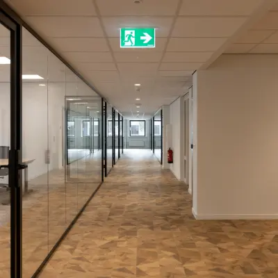 Heldere gang met glazen wanden in kantoorpand, zonder zichtbare personen, op Essebaan 63 in Capelle aan den IJssel, ideaal voor kantoorruimte huren.