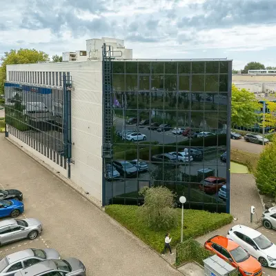 Moderne kantoorpand aan Vlierbaan 20 in Capelle aan den IJssel met reflecterende glazen gevels en omringende parkeerplaats. Een uitstekende locatie voor kantoorruimte huren.