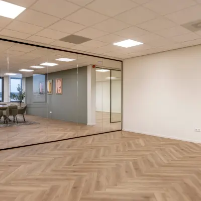 Moderne kantoorruimte aan de Vlierbaan 20, Capelle aan den IJssel, met houten vloer en glazen wand. Ideaal voor bedrijven om kantoor te huren. Grote ramen zorgen voor veel natuurlijk licht.