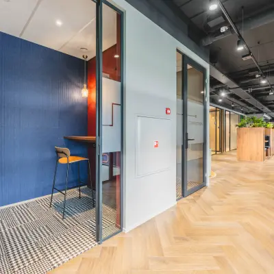 Moderne kantoorpandruimte met glazen wanden en houten vloer op Rijnzathe 12, De Meern. Ideaal voor kantoorruimte huren met lichte werkplekken en groene accenten.