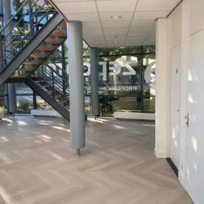 Een lichte entree van het kantoorpand aan Delftechpark 17-19 in Delft met grote ramen en een trap. Ideaal voor kantoorruimte huren met een moderne uitstraling.