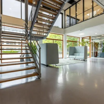 Moderne kantoorruimte huren op Delftechpark 9, Delft met ruime trappenhal, glazen wanden en stijlvolle zitbanken voor een open, lichte sfeer.