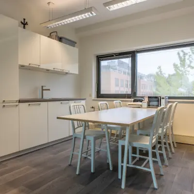 Kantoorruimte met een tafel en zes stoelen bij Delftechpark 9, Delft. Houten vloer en groot raam met uitzicht. Ideaal voor vergaderingen of als gezamenlijke werkplek. Geschikt voor het huren van een kantoorpand.