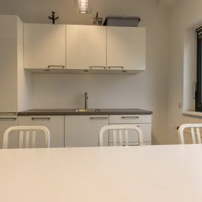 Moderne kantoorruimte in Delft met strakke keukenfaciliteiten en neutrale tinten, ideaal voor ontspanning of informele bijeenkomsten tijdens een drukke werkdag.