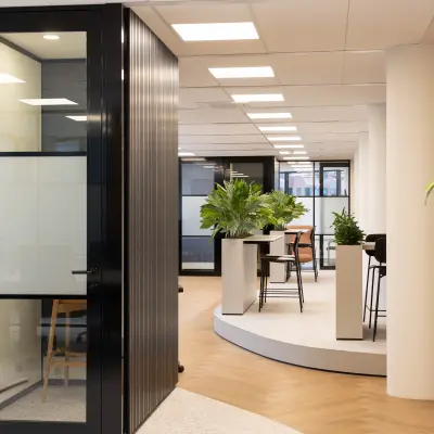 Moderne kantoorruimte met glazen wanden en groene planten op Hambakenwetering 1, Den Bosch. Ideaal om een kantoorpand te huren met stijlvol interieur en ruime werkplekken.