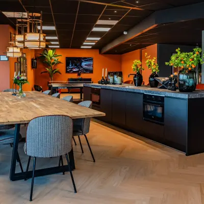 Stijlvolle kantoorkeuken op Reitschweg 1 in Den Bosch, voorzien van een lange houten tafel met gestoffeerde stoelen, perfect om kantoorruimte te huren.