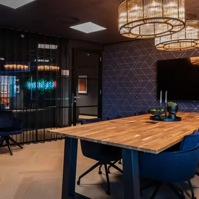 Moderne vergaderruimte in een kantoorpand op Reitschweg 1, Den Bosch, met houten tafel en blauwe stoelen onder stijlvolle verlichting.