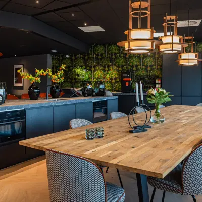 Kantoorruimte huren in Den Bosch aan de Reitschweg 1, met een stijlvolle keuken en eetruimte, voorzien van houten tafel en moderne stoelen, omgeven door zwarte kasten en sfeerverlichting.