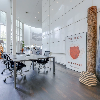 Moderne kantoorruimte huren met open vloerplan en grote ramen op Kalvermarkt 53, Den Haag Centrum. Vergadertafel met stoelen en decoratieve objecten aanwezig.