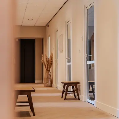 Lichte gang van een kantoorpand op Zeestraat 100, Den Haag Centrum met houten banken en glazen deuren.